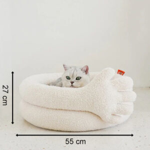Un chat détendu dans un lit mignon en forme de main crémée et douillette.