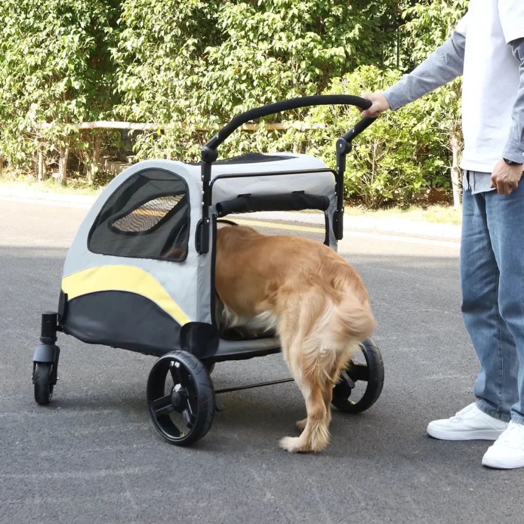 Poussette grise pour chien avec filet de ventilation, poussée sur un chemin de campagne — pratique pour les Corgi qui s'épuisent lors des longues promenades