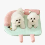 Deux petits chiens blancs heureux sur un coussin pour chien au design cartoon