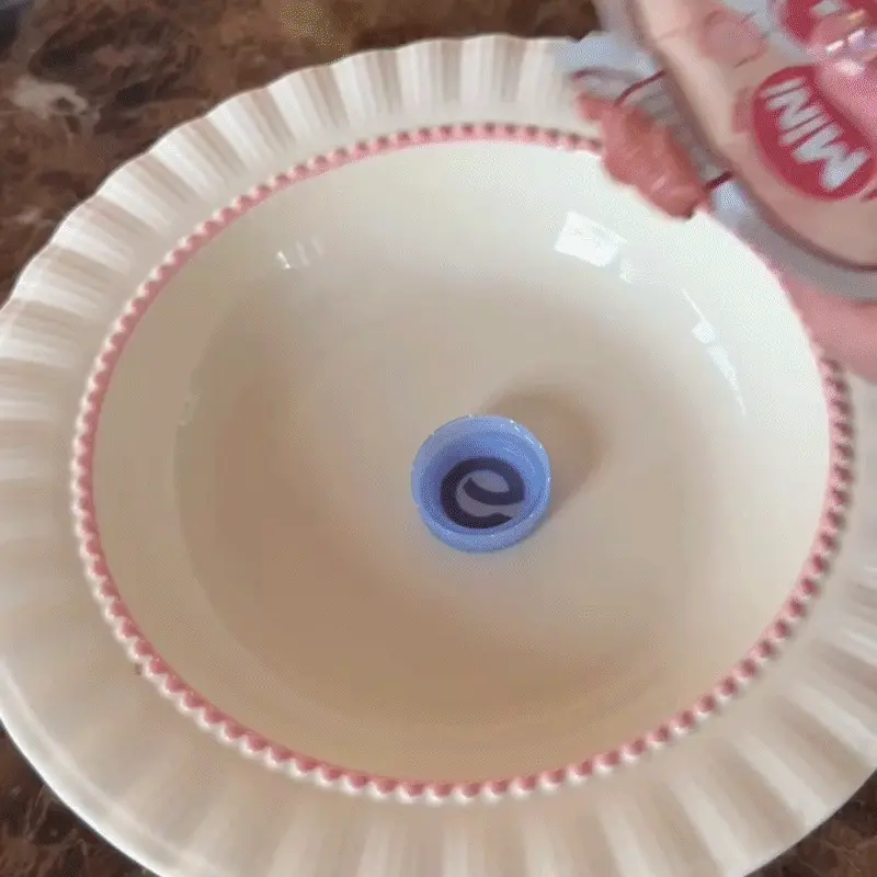 Bouchon de bouteille en plastique flottant dans un bol d'eau pour chat, avec une petite friandise à l'intérieur — technique pour attirer le chat vers l'eau en jouant sur sa curiosité