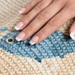 Main posée sur le sisal tissé serré d'un griffoir chat, motif poisson bleu
