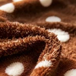 Gros plan sur la peluche bouclette caramel et les pois blancs tuftés