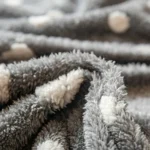 Gros plan sur la peluche bouclette grise et les pois blancs