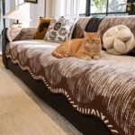 Chat roux allongé sur un jeté de canapé en chenille couleur café