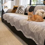 Chat roux allongé sur un jeté de canapé en chenille grise