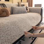 Installation d’un jeté de canapé en chenille beige : on rentre l’excédent sous l’assise