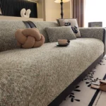 Jeté de canapé en chenille verte sur l’assise d’un canapé, avec un coussin noué