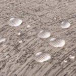 Gouttes d'eau qui perlent sur la chenille grise d'un jeté de canapé imperméable