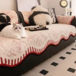 Chat Ragdoll couché sur un jeté de canapé imperméable rouge et blanc à bordure ondulée
