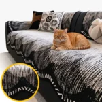 Jeté de canapé antidérapant en chenille noir et blanc à bordure ondulée, avec un chat roux allongé sur un canapé en cuir noir