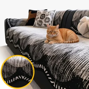 Jeté de canapé antidérapant en chenille noir et blanc à bordure ondulée, avec un chat roux allongé sur un canapé en cuir noir