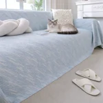 Chat tigré et blanc allongé sur un jeté de canapé 4 saisons bleu ciel
