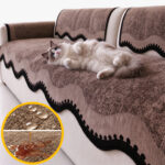 Chat Ragdoll sur le dos, ventre à l’air, sur un plaid canapé imperméable café à bordure ondulée