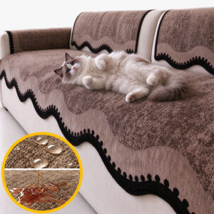 Chat Ragdoll sur le dos, ventre à l’air, sur un plaid canapé imperméable café à bordure ondulée